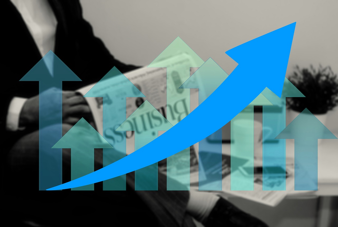 世界地図を背景に、虫眼鏡で特定の部分を拡大している手の写真